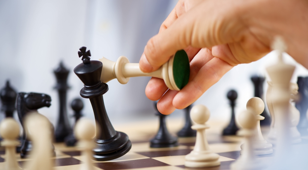 Man hand holding queen and king in checkmate position.